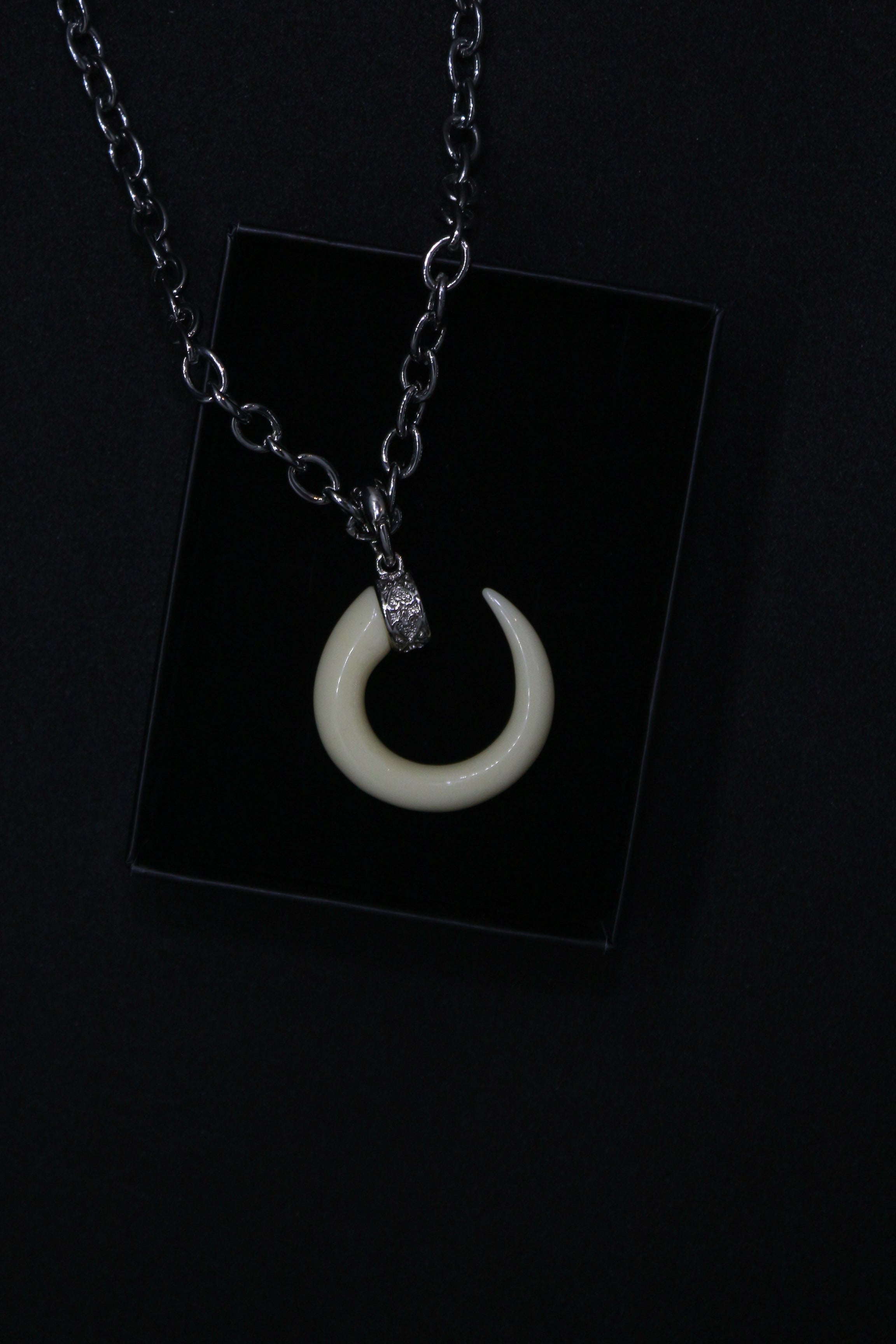 Necklace with a crescent moon pendant on a black card against a dark background