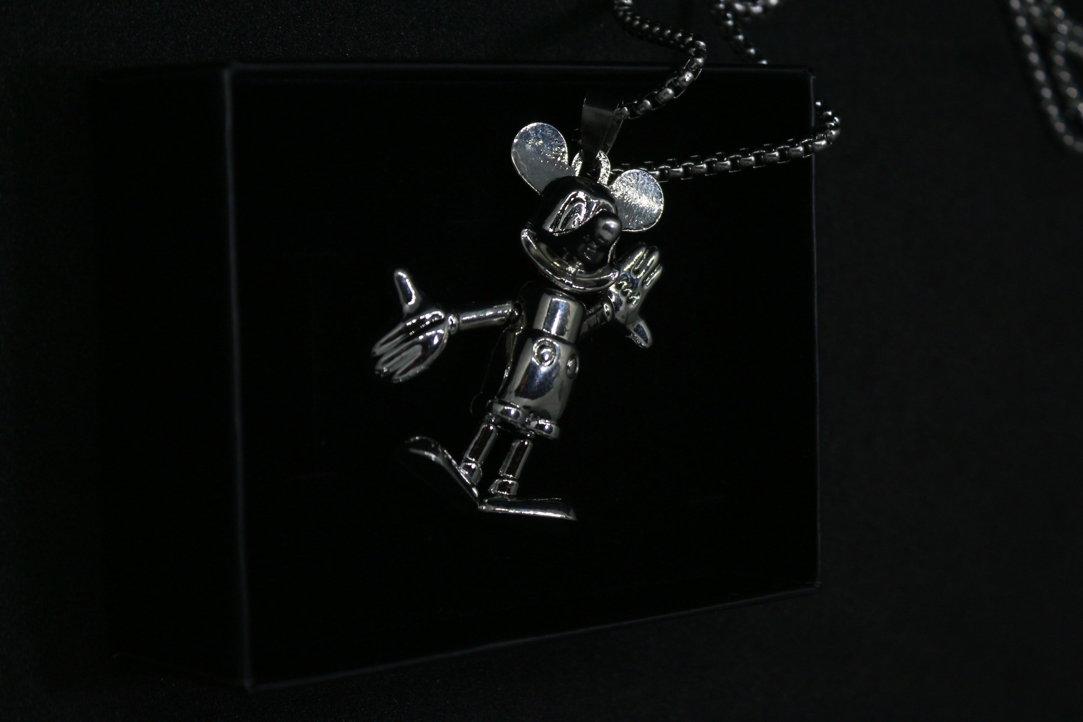 Silver robot pendant on a black background