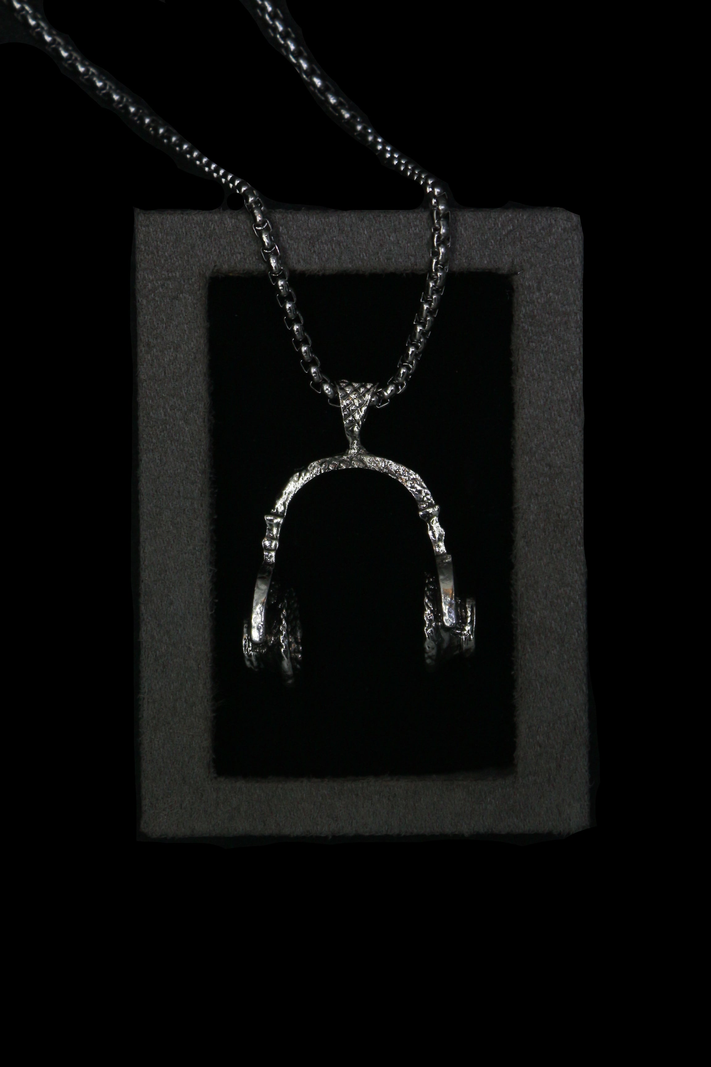 Silver headphone necklace with a pendant on a dark background