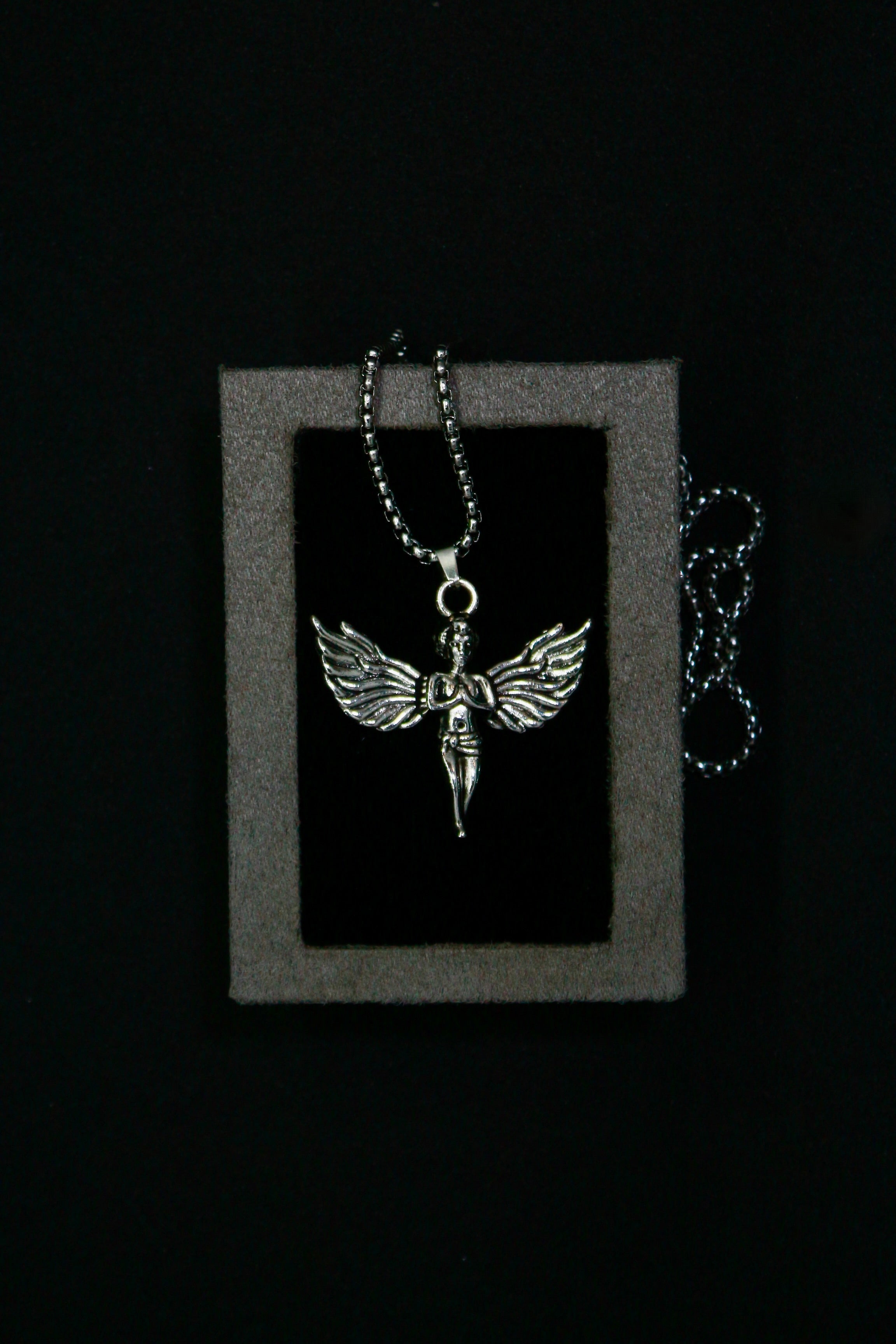 Silver winged pendant necklace on a black background