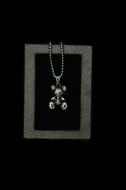 Silver teddy bear pendant necklace on a dark background